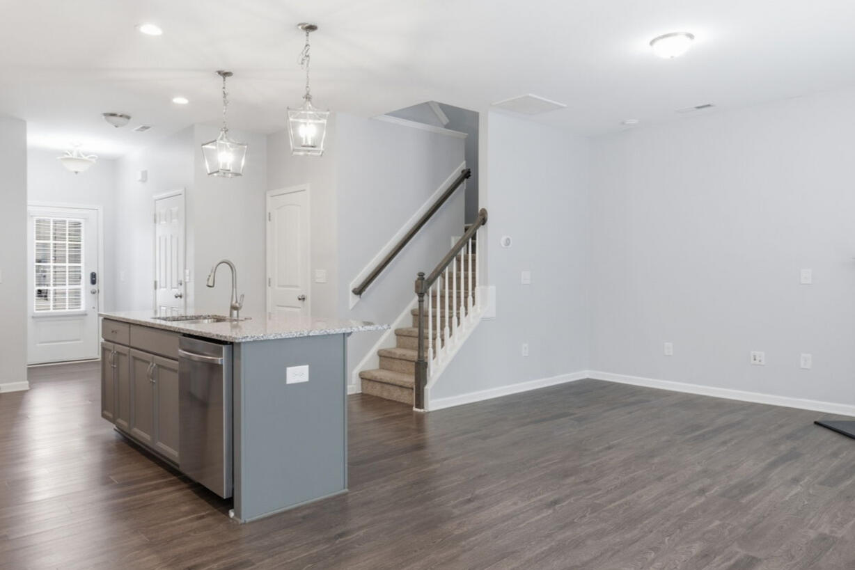 Open-concept living room with fireplace, kitchen island, and staircase in the Garner, NC townhouse rental